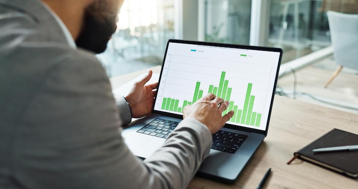 Person sitting at a desk with a laptop and notebook, analyzing real estate investment goals and financial future. Person sitting at a desk with a laptop and notebook, analyzing real estate investment goals and financial future.